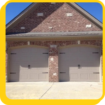 a new set of tan garage doors on a brick house