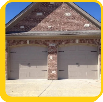 a new set of tan garage doors on a brick house